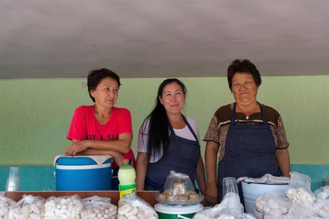 Group of Kazakh woman behind their stand with goat cheese and kumis
