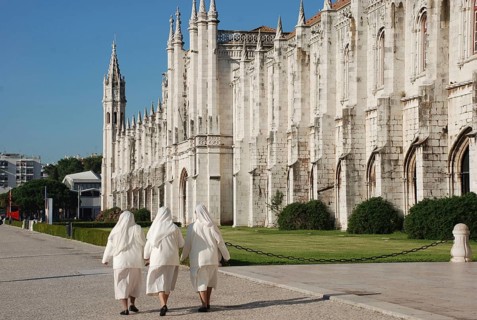 Three nuns walking outside late-Gothic Monastery