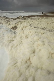 Sea foam washes up on the beach after a storm