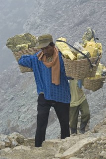 Local men carry sulphur blocks in baskets on the slopes of the volcanic crater