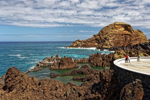 Tourists look from viewing platform at natural lava pools for bathing