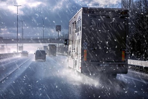 Cars and trucks driving on the motorway in sleet cause dangerous wet road conditions in winter