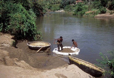 Collecting sand from river on coracle or parisal in Tamil Nadu
