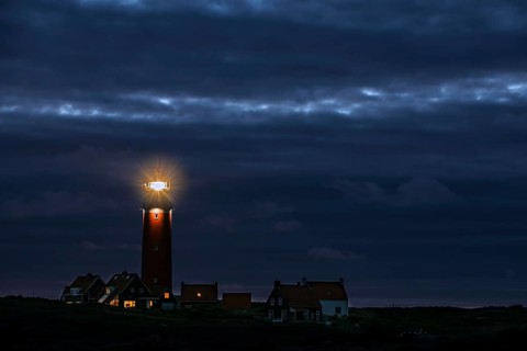 Eierland lighthouse with lantern light over the Wadden Sea at night on the Dutch island of Texel