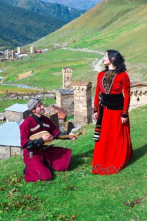 Georgian people from the folklore group playing panduri and dancing in traditional Georgian dress