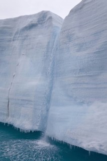 Coastal glacier terminus with waterfall from melting ice