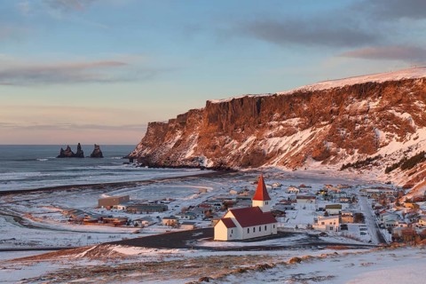 Reynisdrangar sea stack and Vik church in Vik i Myrdal village in winter
