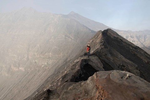 Tourists standing on edge of volcanic crater