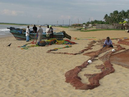 Repairing fishing nets on Negombo beach Sri Lanka