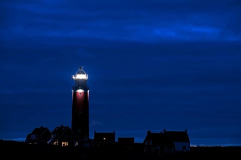 Eierland lighthouse with lantern light over the Wadden Sea at night on the Dutch island of Texel