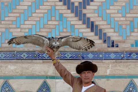 Kazakh man in traditional dress showing his eurasian eagle-owl