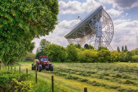 Radio telescope with tractor and baler with silage in foreground