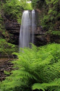Waterfall flowing over a defaced edge of hard sandstone