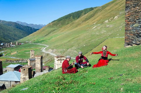 Georgian people from a folkloric group playing panduri and dancing in traditional Georgian dress