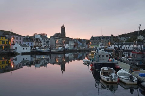 Boats moored in town harbour at sunset