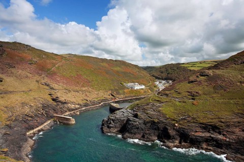 View of the coastline with breakwater and the old quay in the foreground leading to the village in the valley