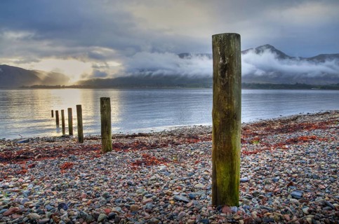 Wooden poles on the shore of the loch at sunset