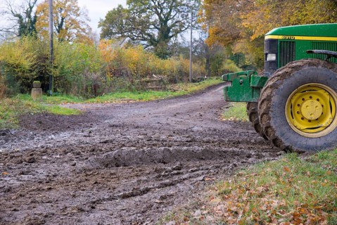 John Deere tractor beside muddy country road