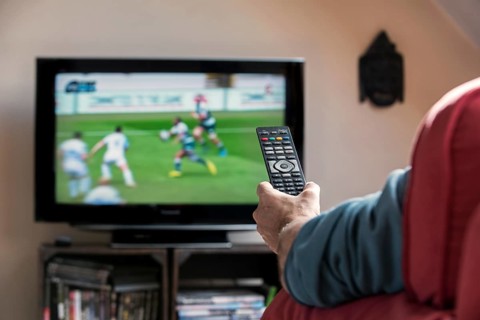 Man with remote control in front of TV