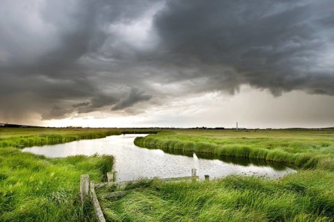 Storm clouds over a pond in coastal grazing marsh habitat