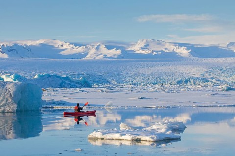 Kayaker in a red kayak on the glacier lagoon Joekulsarlon in winter