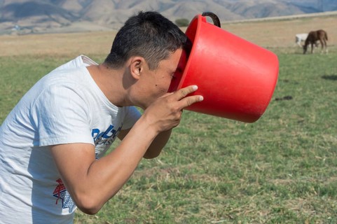 Kazakh man drinking fresh mare's milk from a bucket