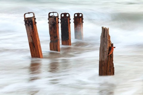 Old wooden groynes with incoming tide at dusk