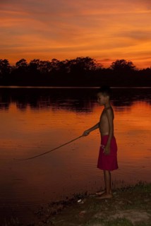 Young fishing in the lake at sunset