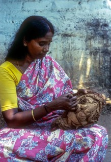A woman carving on the shell of coconut