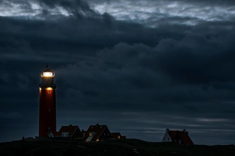 Eierland lighthouse with lantern light over the Wadden Sea at night on the Dutch island of Texel