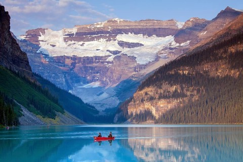 Tourists in a red canoe on glacial Lake Louise with Victoria Glacier