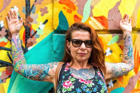 Tattooed woman in front of a wall covered with graffiti