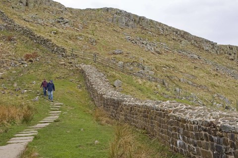 Walkers on the path next to remains of Roman fortifications
