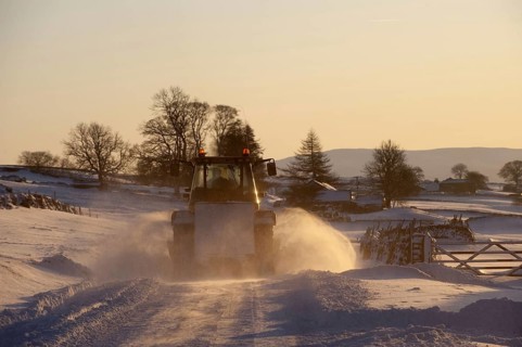 Snow plough clearing snow-covered country road