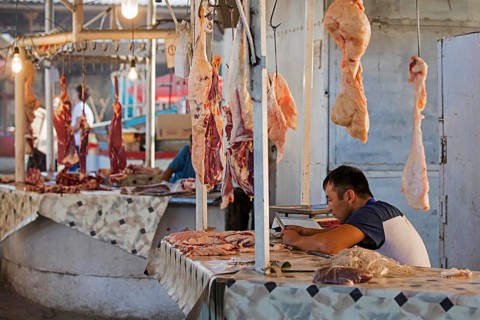 Kyrgyz vendor sells meat at an unhygienic butcher's stall at a food market in the city of Osh on the Silk Road in Kyrgyzstan