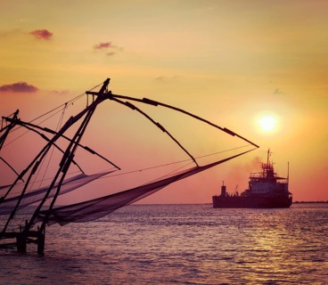 Vintage retro hipster style travel image of Kochi chinese fishnets on sunset and modern ship. Fort Kochin