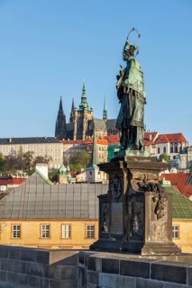 John of Nepomuk or John Nepomucene national saint of the Czech Republic statue on Charles Brigde at the site where the saint was thrown into Vltava with St. Vitus Cathedral in background in Prague