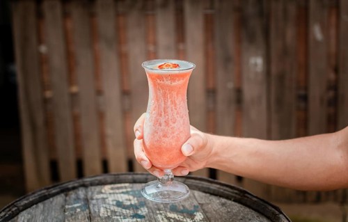 Hands holding strawberry smoothie on wooden table with blurred background. Hands showing strawberry smoothie on wooden table. People hand holding a strawberry milkshake on wood