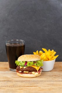 Hamburger cheeseburger fast food meal menu with fries and coke drink on wooden board in Stuttgart