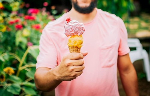 Unrecognizable people holding ice cream in cone outdoors. Front view of person hands holding an ice cream cone. People showing a double ice cream cone. Cone ball ice cream concept