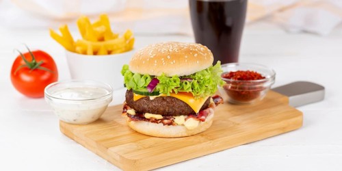 Hamburger cheeseburger fast food meal menu with fries and coke drink on wooden board Panorama in Stuttgart