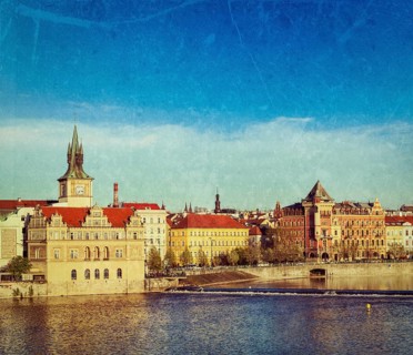 Vintage retro hipster style travel image of Prague Stare Mesto embankment view from Charles bridge on sunset with grunge texture overlaid. Prague
