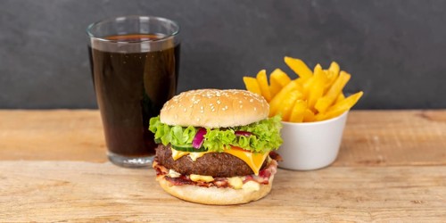 Hamburger cheeseburger fast food meal menu with fries and coke drink on wooden board Panorama in Stuttgart