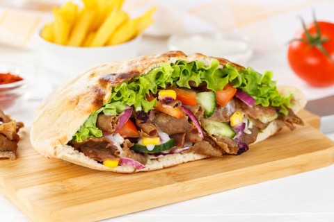 Doener Kebab Doner Kebap half fast food meal in pita bread with fries on wooden board in Stuttgart