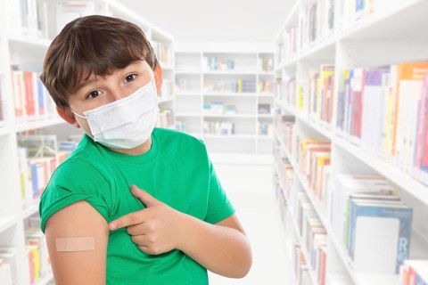 Child boy pointing finger at plaster in school at children vaccination mask against corona virus corona virus text free space copyspace in Stuttgart
