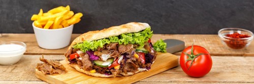 Doener Kebab Doner Kebap fast food meal in pita bread menu with fries on wooden board Panorama in Stuttgart