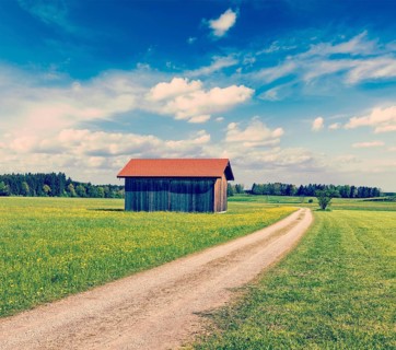 Vintage retro effect filtered hipster style image of rural road in summer meadow with wooden shed. Bavaria