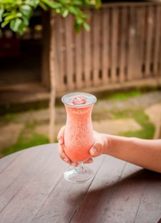 Top view of hand holding a strawberry milkshake on table