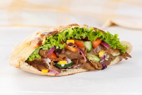 Doener Kebab Doner Kebap half fast food meal in pita bread on wooden board in Stuttgart