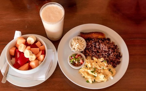 Gallo pinto breakfast served on the table with a fruit salad